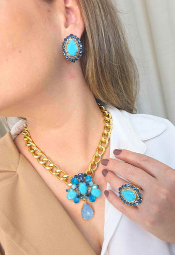 Anel Paola Turquesa: Clássico Oval com Pedras Azuis no Dourado | Design Premium