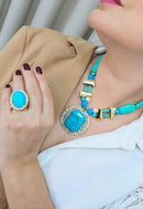 Anel Nina oval com pedras azul turquesa e cristal banhado no dourado