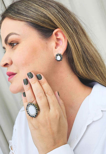 Brinco Fascínio oval com pedras brancas e hematite banhado no ouro velho
