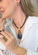 Colar Potira de cordão marrom e pedra de gota azul com detalhes em dourado