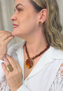 Colar Flamboyant com pingente dourado e cascalhos de resina amarronzadas no banho dourado
