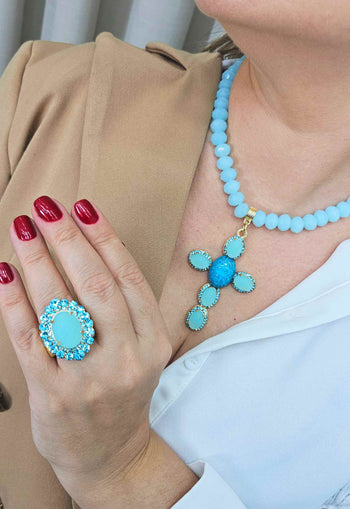 Colar Oásis com pingente de crucifixo de pedras azuis banhado no dourado