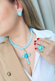 Colar Oásis com pingente de crucifixo de pedras azuis banhado no dourado