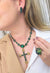 Colar Cindy com pingente de crucifixo de pedras verdes banhado no ouro velho